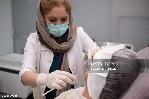 Medical personnel injects fat under the skin of Masoumeh Ataeis face, who is a victim of an acid attack, during the restorative operation of the fat...