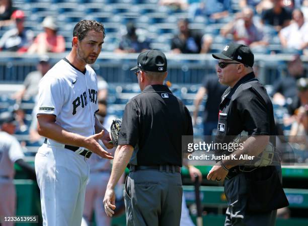 Chase De Jong of the Pittsburgh Pirates is checked for sticky substances by umpires Jerry Meals and Marvin Hudson against the Chicago White Sox...