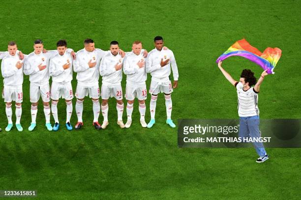 Person waving the rainbow flag runs on the pitch as the Hungary players line up for the national anthems the UEFA EURO 2020 Group F football match...