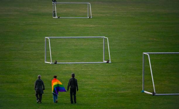 People walk with a Rainbow flag on a football field in Cologne, western Germany, on June 23, 2021. - With Germany due to play Hungary on June 23,...