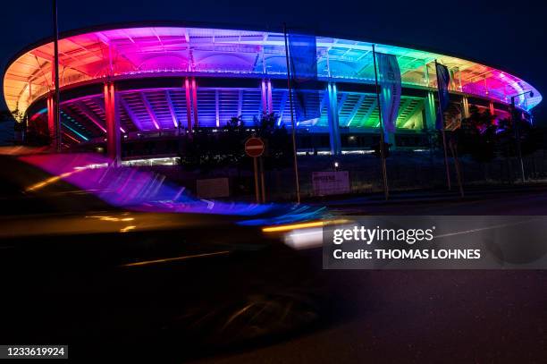 Car drives past the Deutsche Bank Park stadium illuminated with the Rainbow colours, in Frankfurt am Main, western Germany, on June 23, 2021. With...