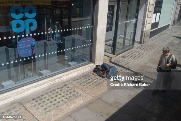 Wealthier man looks down at a male lying on the pavement outside a branch of the Co-Op bank on the Strand, on 23rd June 2021, in Westminster, London,...