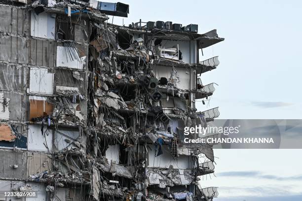 Rubble hangs from a partially collapsed building in Surfside north of Miami Beach, on June 24, 2021. - The multi-story apartment block in Florida...