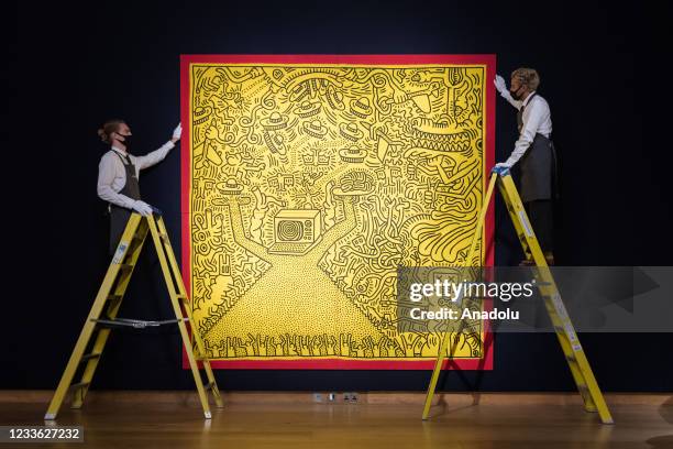 Staff members pose with 'Untitled' by Keith Haring estimate Â£3 000 - 4 000 during a photo call for the 20th/21st Century: London Evening Sale at...