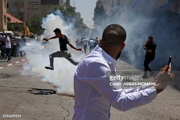 Protesters run for cover from tear gas fired by Palestinian security forces during a demonstration calling for Palestinian president Mahmud Abbas to...