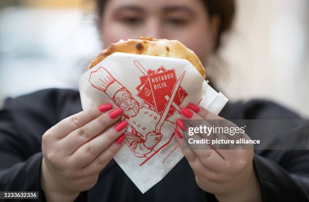 June 2021, Lower Saxony, Osnabrück: A curatorial assistant holds a kebab sandwich in her hands. The packaging bears the imprint "Kutadgu Bilig" . The...