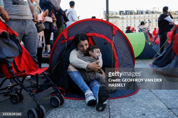 Woman and a child sit in a tent after homeless migrants and their supporters installed tents during an action organised by French association...