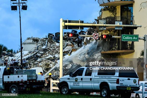 Search and Rescue personnel work as Miami Dade firefighters spray waterat a partial collapse building in Surfside, Miami Beach, on June 24, 2021. - A...