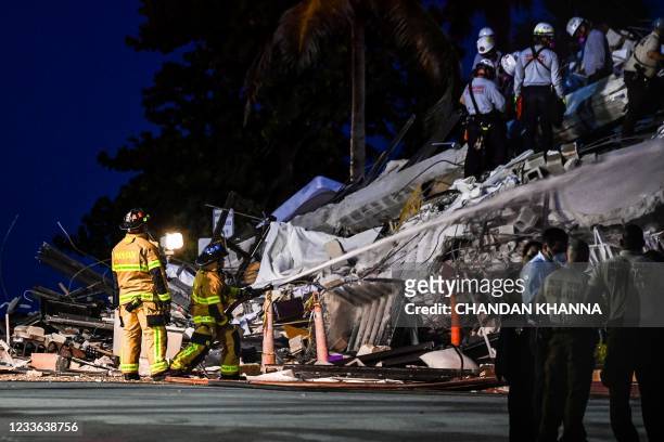 Search and Rescue personnel work as Miami Dade firefighters spray waterat a partial collapse building in Surfside, Miami Beach, on June 24, 2021. - A...