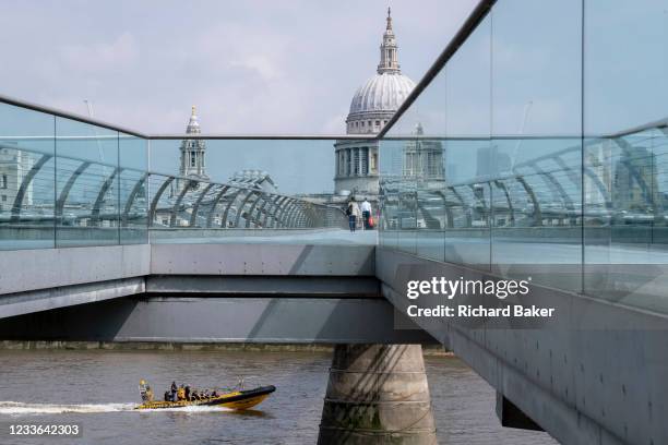 With the dome of St Paul's cathedral in the distance, a Thames Rib Experience boat speeds on the river Thames and beneath the Millennium Bridge, on...