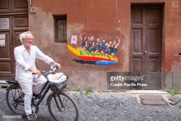 Man passes by the wall with a mural made by Italian street artist Harry Greb named "Enjoy - Tutti al mare" in via dei Montecatini in Rome featuring...