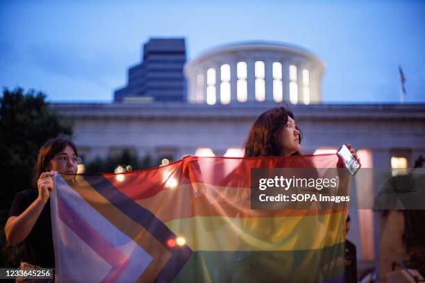 Transgender rights advocates hold pride flags during a rally against Ohio legislation banning transgender women from female sports. Transgender...