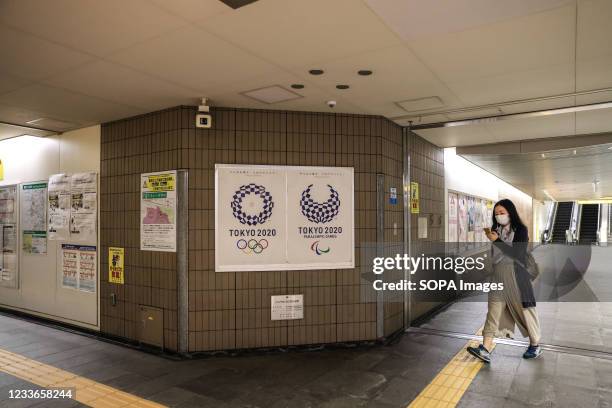 Woman a wearing face mask as a preventive measure against Covid-19 walks past Tokyo 2020 Olympic Games Poster inside a subway station near the...