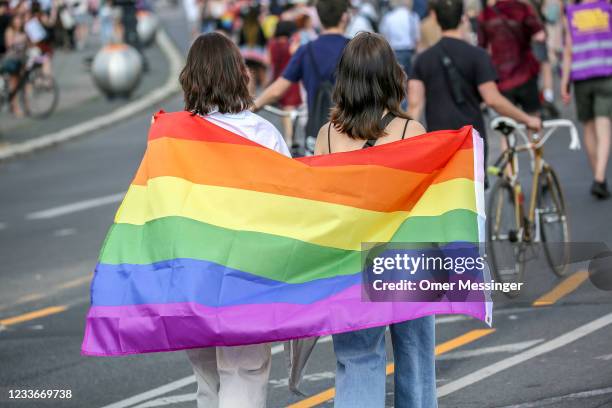 Two women hold the rainbow pride flag as they take part in the Queerschutz Now! march through Unter den Linden street in commemoration and...