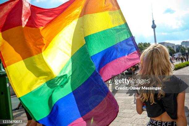 Participant holds the rainbow pride flag in the Queerschutz Now! march through Karl-Marx-Allee street in commemoration and celebration of Christopher...