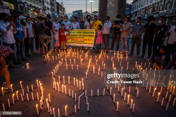 Kashmiri youth hold up a banner as they burn candles to observe the International Day against Drug Abuse and Illicit Trafficking in the city square...