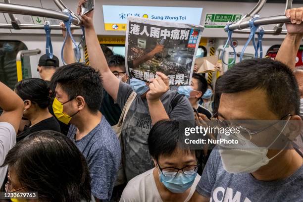 Passengers holds up an apple daily newspaper while riding on the first train of the Tuen Ma Line in Hong Kong, Sunday, June 26, 2021. Today the MTR...