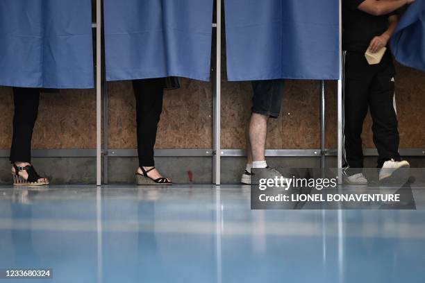 Voters choose their ballots in the polling booths at a polling station in Martres-Tolosane, for the second round of the French regional elections on...