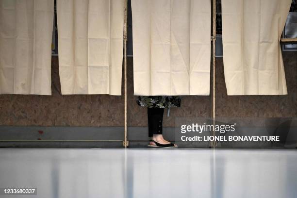 Voter chooses her ballots in a polling booth at a polling station in Martres-Tolosane, for the second round of the French regional elections on June...