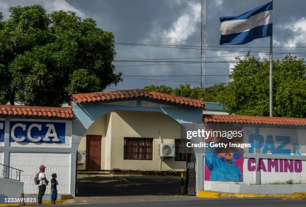 Man and his son stand in front of a billboard with a picture of Nicaraguan President Daniel Ortega at Ministry of Family Economy on June 27, 2021 in...