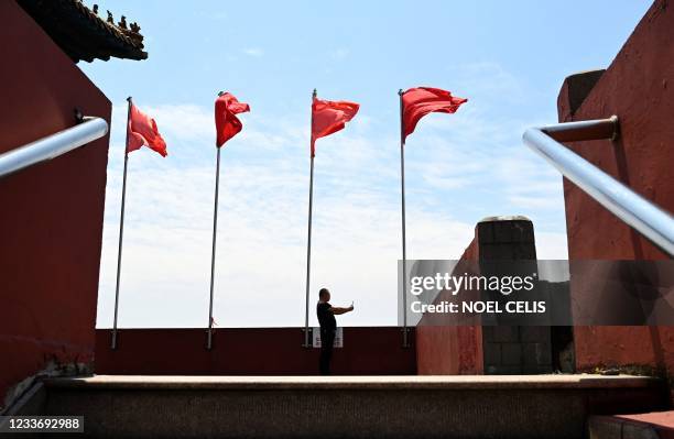 This photo taken on May 21, 2021 shows a man taking pictures at a lookout replica of the Forbidden City at a park in the village of Huaxi in China's...