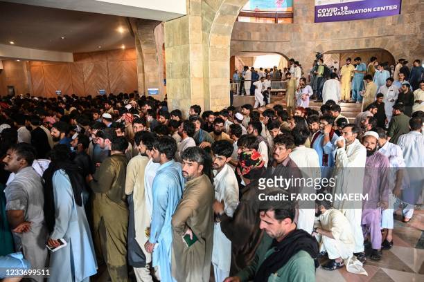 People including overseas Pakistani workers who want to fly to the Middle East stand in a queue to register before receiving a dose of the Pfizer...
