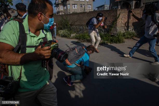 Journalists move run towards safer places amid firing outside residential houses where suspected militants took refuge during a gun battle on June 28...