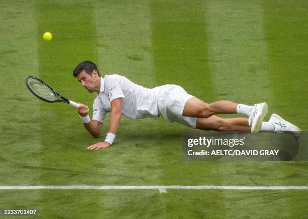 Serbia's Novak Djokovic slips on the grass as he plays a return against Britain's Jack Draper during their men's singles first round match on the...