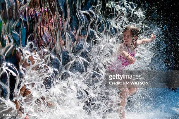 Young girl splashes through a waterfall at a park in Washington, DC, on June 28 as a heatwave moves over much of the United States. Swathes of the...