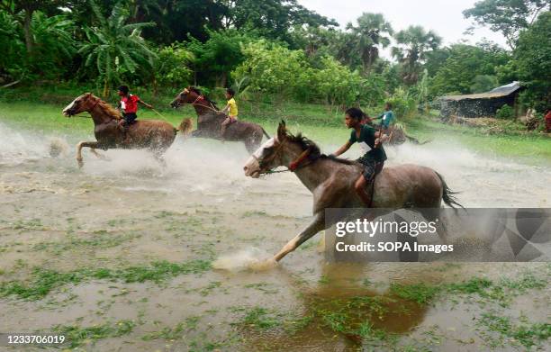 Child jockeys ride horses during a Horse Race in submerged fields. After harvest season when the fields are submerged in water the cattle and horse...