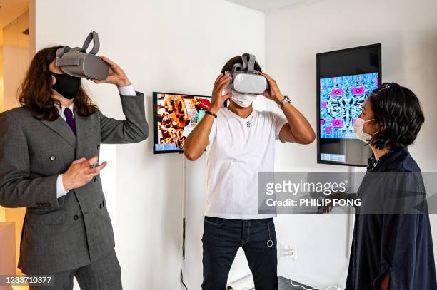 This picture taken on June 25, 2021 shows CEO of the BAE, a crypto art platform, and the exhibition's curator, Sascha Bailey , demonstrating a...