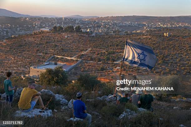 Israeli settler youths lift an Israeli flag in the newly-established wildcat outpost of Eviatar near the northern Palestinian city of Nablus in the...