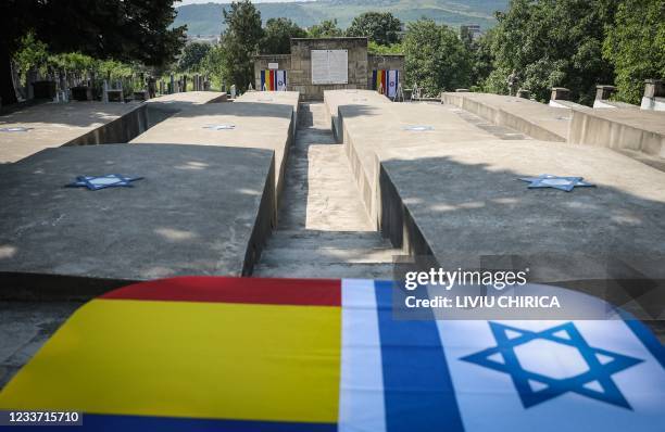 Romanian and an Israeli flag lie on the monument of the Jewish victims of the Iasi pogrom at the Jewish cemetery in Iasi, Romania, on June 29, 2021....