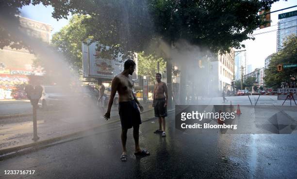 Residents walk through a temporary misting station on Abbott Street during a heatwave in Vancouver, British Columbia, Canada, on Monday, June 28,...