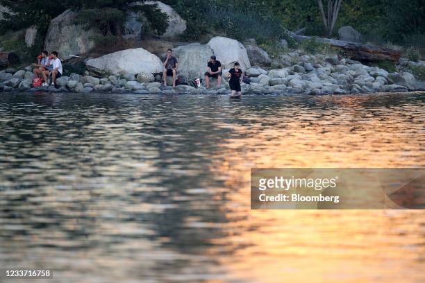 People sit by the water in False Creek on Habitat Island during a heatwave in Vancouver, British Columbia, Canada, on Monday, June 28, 2021. The heat...