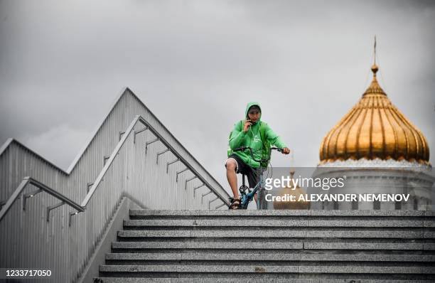 Food delivery courier talks on the phone in front of Christ-the-Saviour cathedral, the main Russian Orthodox church in central Moscow, on June 29...