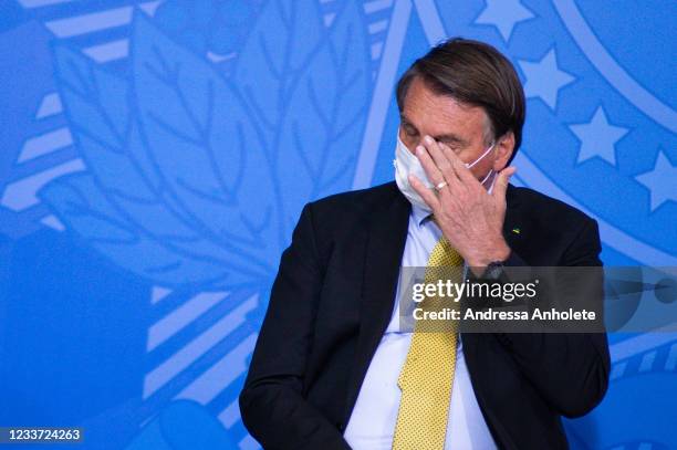 President of Brazil Jair Bolsonaro touches his face during an event to launch a new register for professional workers of the fish industry at...