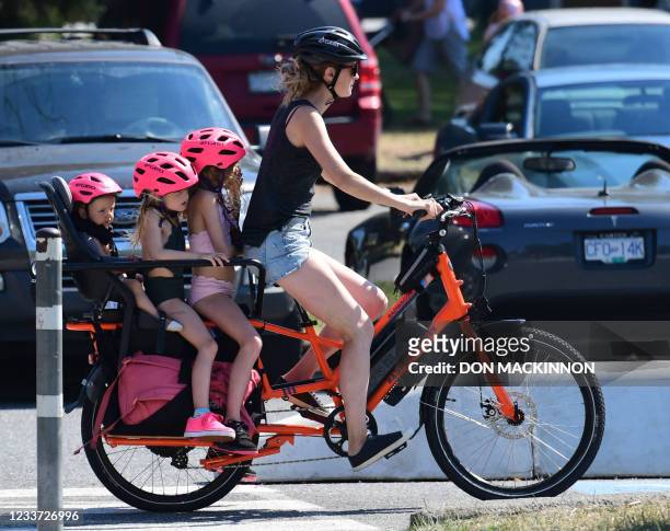 Woman and three children go on a cooling bike ride on a scorching hot day, in Vancouver, British Columbia, June 29, 2021. - Schools and Covid-19...