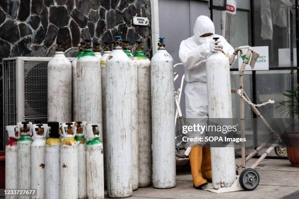 Health worker wearing Personal Protective Equipment arranges oxygen cylinders inside the Wisma Atlet Covid-19 Emergency Hospital complex. Indonesia...