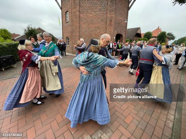 June 2021, Lower Saxony, Saterland: The folk dance troupe Saterland performs traditional dances in front of the mill Scharrel. The occasion is a...