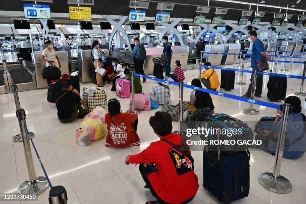 Travellers, mostly Myanmar passengers, wait for their flight to Yangon at the check-in area of Suvarnabhumi Airport in Bangkok on June 30 amid an...