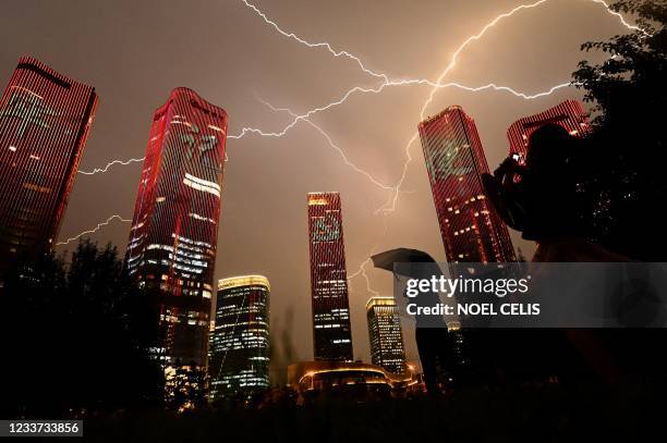 Bolt of lightning crosses the sky as people look at buildings displaying a light show on the eve of the 100th anniversary of the Chinese Communist...