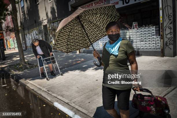 Pedestrian carries an umbrella for protection from the sun during a heatwave in the Brooklyn borough of New York, U.S., on Wednesday, June 30, 2021....