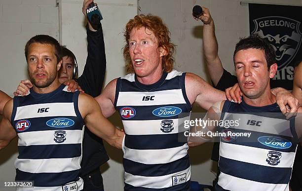 David Wojcinski, Cameron Ling and Shannon Byrnes of the Cats sing the song in the rooms after winning the round 24 AFL match between the Collingwood...