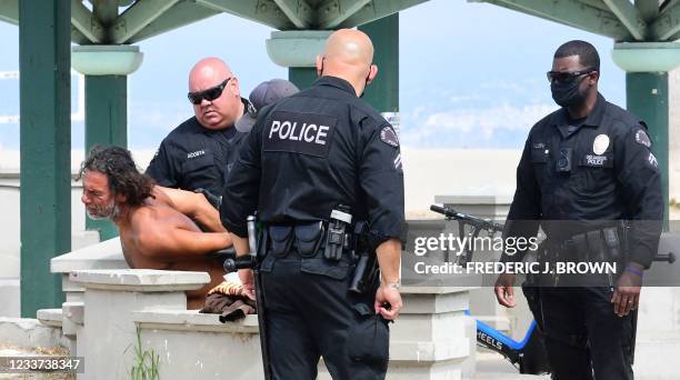 Los Angeles Police Department officers detain a homeless man along the Ocean Front Walk in Venice, California on June 30 where an initiative began...