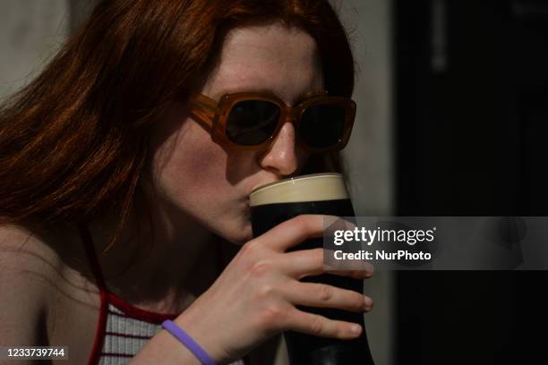 Young woman enjoys a pint of Guinness in a pub in Dublin city center. On Wednesday, 30 June 2021, in Dublin, Ireland.