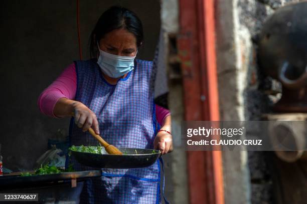 Gris, a member of the collective Mujeres de la Tierra , cooks in Milpa Alta, Mexico City, on June 21, 2021. - Mujeres de la Tierra was created in May...