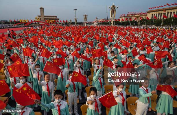 Chinese students wave party and national flags at a ceremony marking the 100th anniversary of the Communist Party at Tiananmen Square on July 1, 2021...