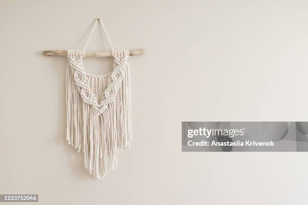 hand made natural cotton macrame decoration hanging on white wall. wall panel in boho style made of cotton threads in natural white color using the macrame technique for home decor and wedding decoration. - macrame stock-fotos und bilder