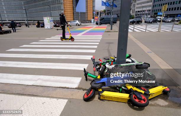 Man rides his electric kick scooter on a crosswalk beside a pack of motorized scooters on July 1, 2021 in Brussels, Belgium.